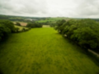 Flat design showing grassy meadow with tree borders, rolling hills under cloudy sky with dirt track