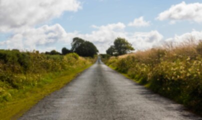 Asphalt road amidst field against sky