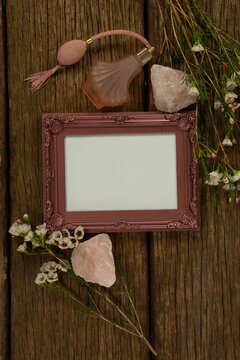 Photo frame, perfume and flowers on wooden table