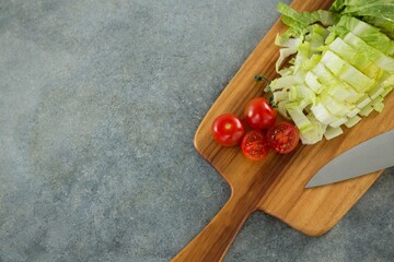 Chopped lettuce with tomato on cutting board
