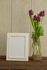 Photo frame and flower vase on table