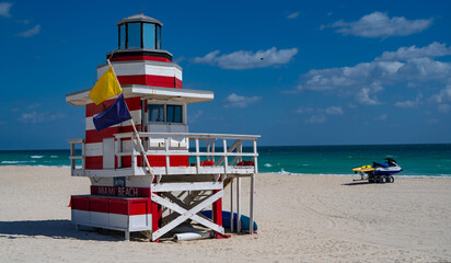 Fototapeta premium Miami Beach lifeguard at the summer beach. Tourism on South Miami Beach. Sky above lifeguard tower in Miami. Iconic lifeguard tower on sand in Miami. A symbol of Miamis coast.