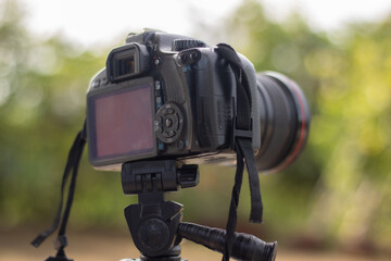 A professional DSLR camera and lens mounted on a tripod in a natural, outdoor setting. An image representing landscape photography, preparation, patience, and professional gear.

