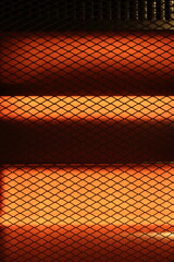 A dark mesh pattern set against a vibrant orange backdrop, generating a sense of warmth, texture,...