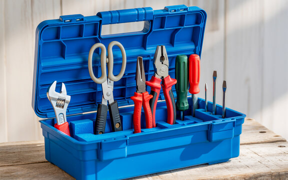 A photograph of an open blue toolbox displaying assorted hand tools in foam cutouts, neatly arranged and fully visible on a wooden surface