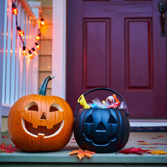 Happy Halloween carved pumpkin and candy bucket on front porch steps