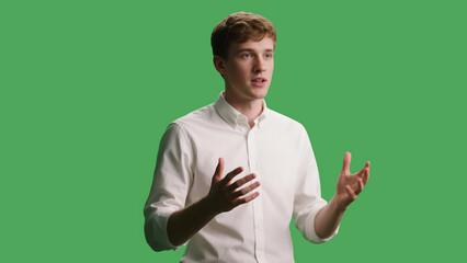 Young man in white shirt speaking with expressive hand gestures on a green screen