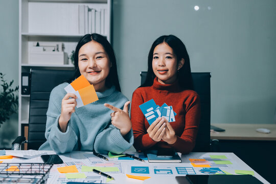 UX UI designer testing prototype on a phone, discussing and brainstorming on wireframes for a website and mobile app prototype, in the concept of website and mobile application design concept.