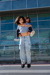 low angle view of a girl in striped t-shirt and jeans jumping with smaller girl carried on her back