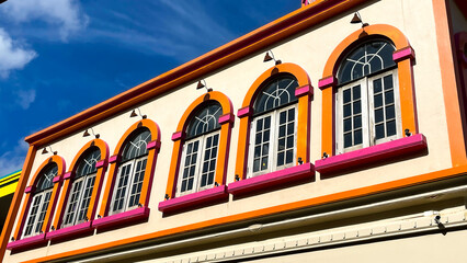 Bottom view of colorful facade with many arched windows against blue sky. Facade design in Thailand.