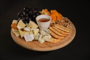 Cheese plate of color cheeses variety, yellow, white and blue gorgonzola platter, munster, fourme cheese board, assorted chopped dairy products, many stinky French cheeses on wood

