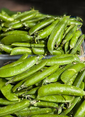 Top view of fresh green peas placed in plastic containers Close-up of vegetables at local market.
