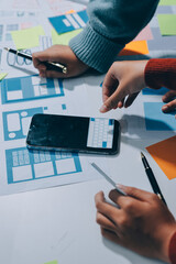 UX UI designer testing prototype on a phone, discussing and brainstorming on wireframes for a...