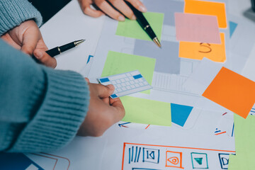 UX UI designer testing prototype on a phone, discussing and brainstorming on wireframes for a...