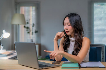 woman is sitting at a desk with a laptop