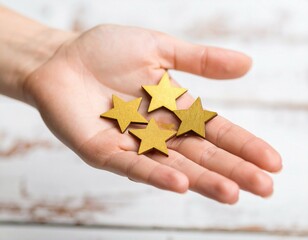 Hand holding four shiny golden stars on a light wooden background