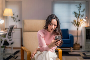 woman is sitting in a chair and looking at her cell phone