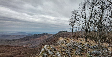 A moody view from the rocky edge of Őr-kő plateau, overlooking the forested ridges of the western Bükk Mountains under a dramatic sky.
