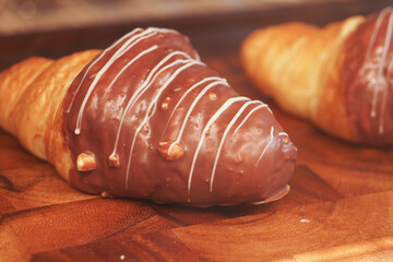 Delicious chocolate-coated croissant on wooden board