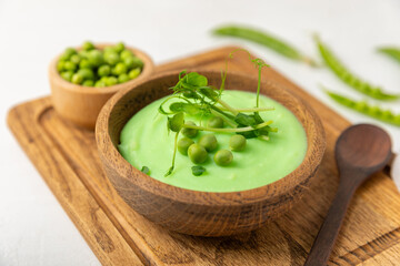 Green pea soup on a wooden table. Fresh pea soup bowl. Delicious healthy cream soup in a bowl with green peas and croutons. Healthy vegan puree. Copy space. Space for text.