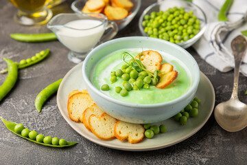 Green pea soup on a wooden table. Fresh pea soup bowl. Delicious healthy cream soup in a bowl with green peas and croutons. Healthy vegan puree. Copy space. Space for text.