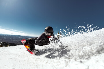 Extreme freerider snowboarder in the backcountry sprays fresh snow under the bright winter sun...