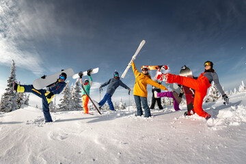 Large group of skiers and snowboarders having fun on snowy slope against blue sky