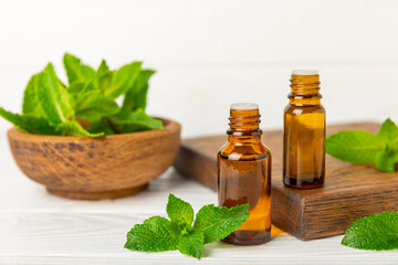 Essential oil mint on a wooden background. Peppermint essential oil with fresh mint leaves. A bottle of aromatherapy oil. Mint extract. The concept of natural cosmetics, spa care. copy space