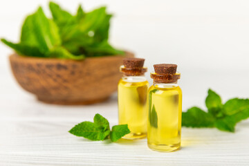 Essential oil mint on a wooden background. Peppermint essential oil with fresh mint leaves. A bottle of aromatherapy oil. Mint extract. The concept of natural cosmetics, spa care. copy space