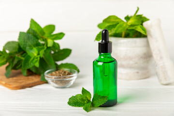 Essential oil mint on a wooden background. Peppermint essential oil with fresh mint leaves. A bottle of aromatherapy oil. Mint extract. The concept of natural cosmetics, spa care. copy space