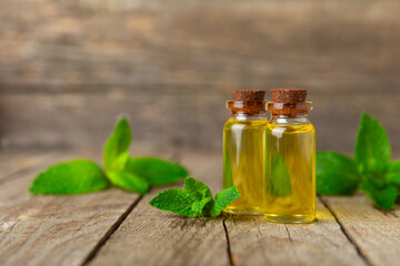 Essential oil mint on a wooden background. Peppermint essential oil with fresh mint leaves. A bottle of aromatherapy oil. Mint extract. The concept of natural cosmetics, spa care. copy space