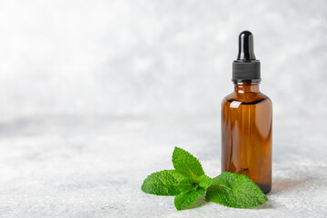 Essential oil mint on a wooden background. Peppermint essential oil with fresh mint leaves. A bottle of aromatherapy oil. Mint extract. The concept of natural cosmetics, spa care. copy space