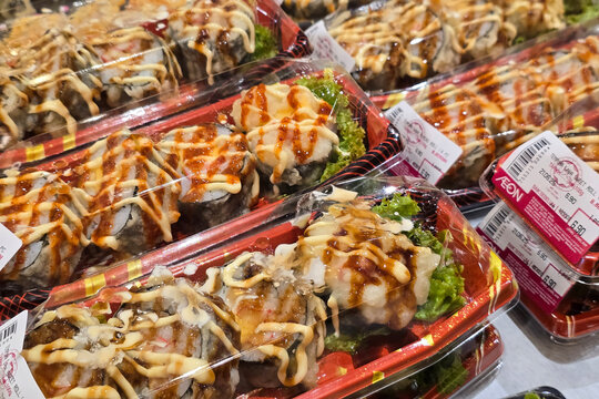 Penang, Malaysia &ndash; Jun 21, 2025: Close-up view of assorted tempura sushi rolls drizzled with mayonnaise and sweet sauces, neatly packed and displayed for sale at AEON supermarket.
