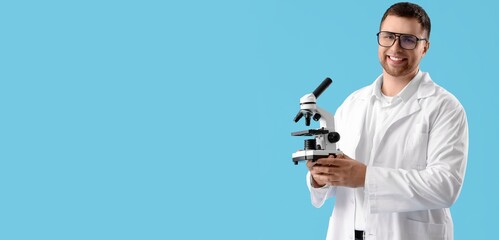 Male scientist with microscope on blue background with space for text