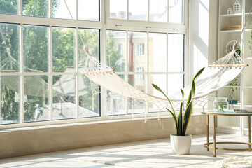 Interior of light living room with hammock and coffee table