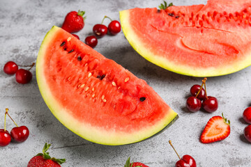 Pieces of fresh watermelon, melon and cherries on grey background