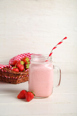 Mason jar of tasty strawberry smoothie on table
