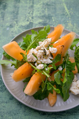 Plate of melon and arugula salad. Fresh, light summer dish with vibrant colors and healthy ingredients