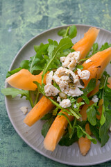 Plate of melon and arugula salad. Fresh, light summer dish with vibrant colors and healthy ingredients