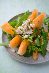 Plate of melon and arugula salad. Fresh, light summer dish with vibrant colors and healthy ingredients