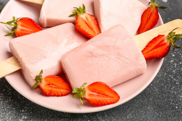 Plate with sweet strawberry ice-cream popsicles on grey background