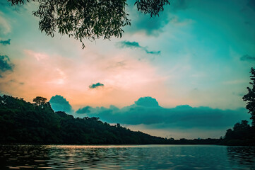 Scenic river landscape at sunset with golden light reflecting on calm water and lush green surroundings. Ideal for nature themes, eco travel visuals, and tranquil outdoor designs