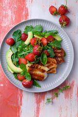 Plate of summer salad with fresh strawberries, arugula, and grilled halloumi cheese. Bright, flavorful, and healthy dish perfect for warm seasons.