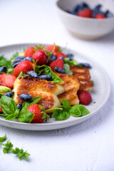 Plate of summer salad with fresh strawberries, arugula, and grilled halloumi cheese. Bright, flavorful, and healthy dish perfect for warm seasons.