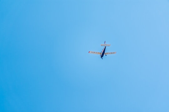 Small ultralight airplane with overhead wing and single propeller flying in sunset sky.