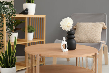 Light wooden coffee table with shelving unit and armchair near grey wall