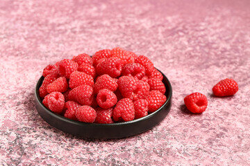 Tray with fresh raspberries on purple background