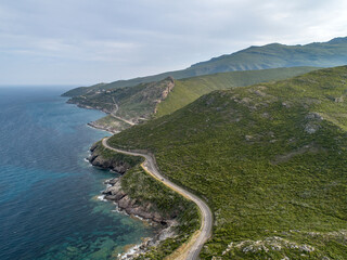 Aerial view car Roadtrip Winding road along rocky coast of Cap Corse peninsula on Corsica island France