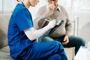 Senior man with chest pain speaks to nurse noting symptoms on tablet at home. Healthcare, heart...