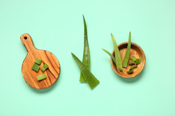 Cutting board and bowl with aloe vera leaves on turquoise background